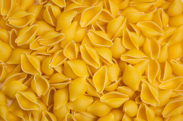 istock Trendy flat view closeup yellow macaroni. Conchiglie. Top view, flat lay. Nature concept. Texture background, pattern. Restaurant work concept. Ready for print, copy space. 1342610156