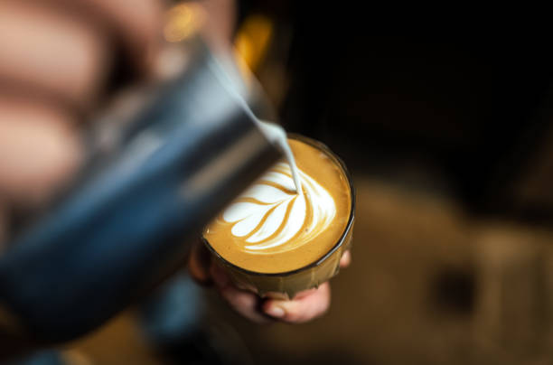 Close up of hand pouring coffee latte art stock photo