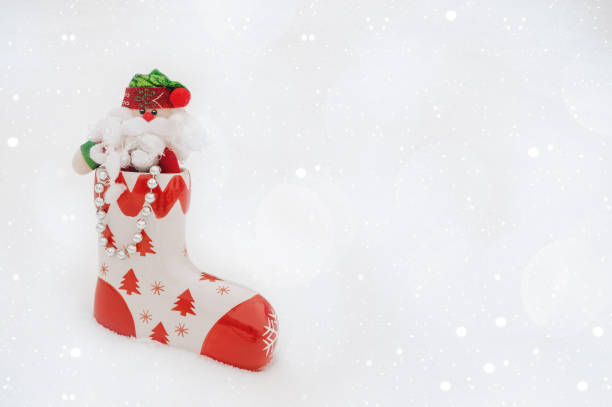 istock santa claus ' ceramic boot stands in the snow. Toy Santa in a boot. copy space 1342614708