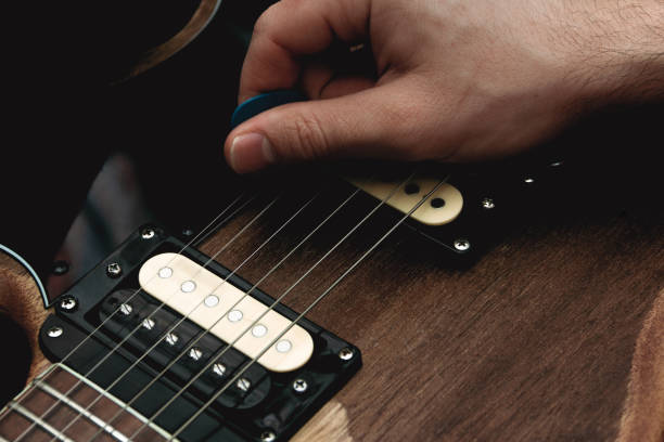 person plucking the strings of an electric guitar with a pick. selective focus. copy space. - plucking an instrument imagens e fotografias de stock