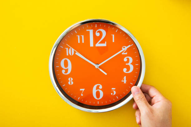 istock Hand holding alarm clock on isolated yellow background. 1342617418