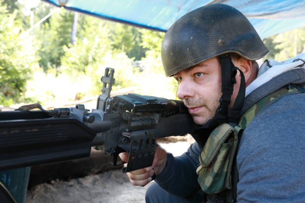 istock Man in military helmet aims with light machine gun 1342619903