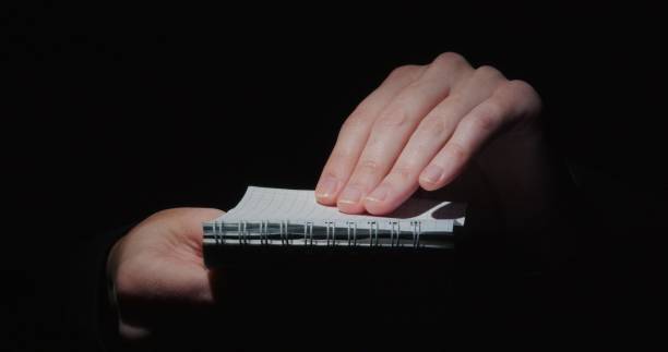 istock Human hands are holding a page of note pad against black background 1342620898