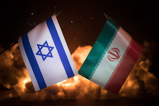 Israel and Iran small flags on burning dark background. Concept of crisis of war and political conflicts between nations. Selective focus