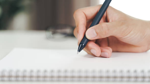 istock Close up of young man in casual cloth hands writing down on the notepad, notebook using ballpoint pen on the table. 1342626675