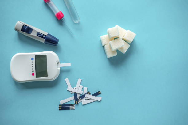 medicine, diabetes diagnostics, healthcare. concept. top view of a blood glucose meter and test strips checking blood sugar levels at home stock photo
