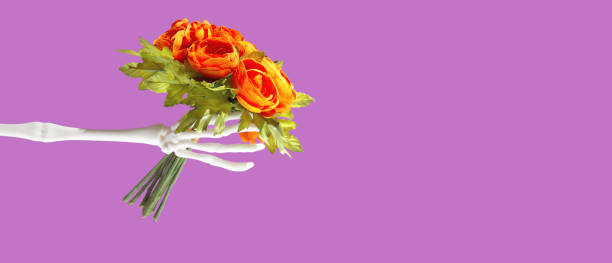 Halloween love creative and bizarre concept with two skeleton arms and flowers. Present for holiday.