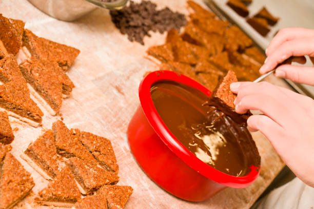 istock Confectioner covering nut wedges with chocolate 1342632262