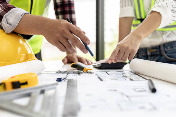 istock Engineers and architects pointing to the house blueprints designed for the client, meeting atmosphere, they meet together to plan the construction and fix it. Design and interior design ideas. 1342632734