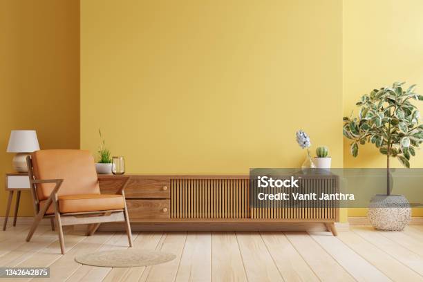 Cabinet Tv In Modern Living Room With Leather Armchair And Plant On Yellow Wall Background Stock Photo - Download Image Now