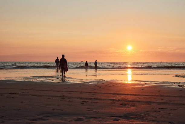 istock A silhouette of people walking on a sea shore at sunset 1342655607