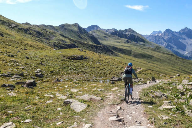 istock Woman mountain bikes along sunny bike path 1342698946