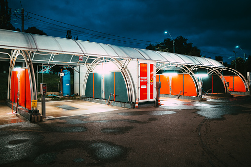 Deva, Romania - 22 September, 2021: An empty self service car wash illuminated at night in a deserted parking lot.