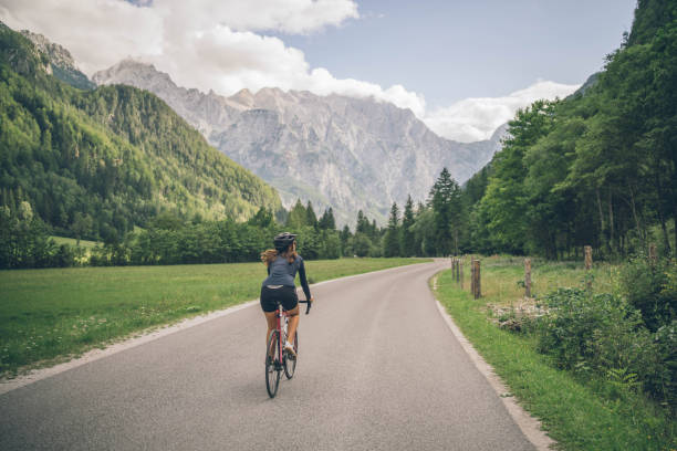 rennradfahrerin fährt auf sonniger landstraße - cyclist cycling road women stock-fotos und bilder