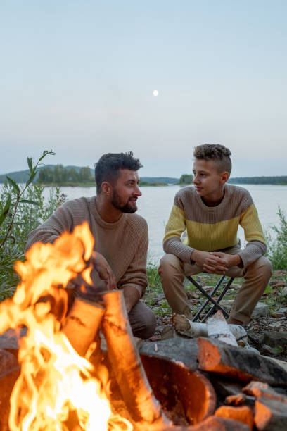 istock Young father and son sitting by campfire in the evening 1342714808