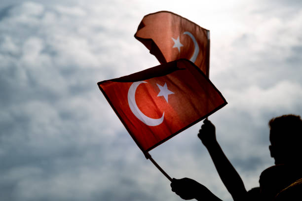 dos manos sosteniendo banderas turcas en un cielo azul y nublado y en el día de la libertad esmirna. - agosto fotografías e imágenes de stock