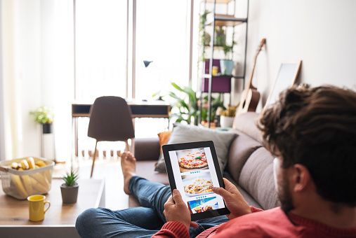 Adult man is ordering food online at home.