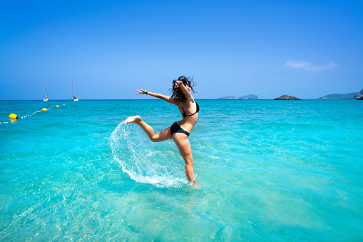 Ibiza beach girl splashing water jump in Balearic islands