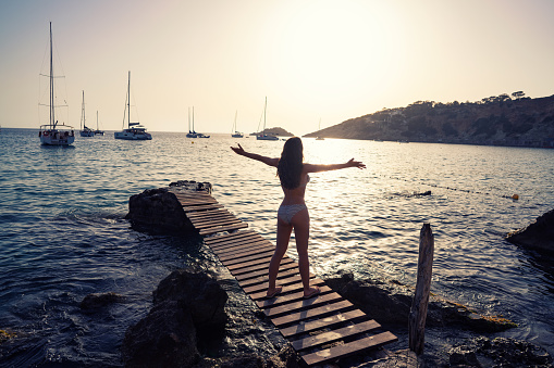 Ibiza cala d Hort girl open arms on pier sunset Es Vedra islet Balearic Islands