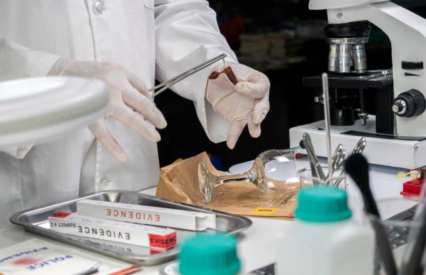 Ekspert policyjny pobiera próbkę krwi z potłuczonego szklanego kubka w laboratorium kryminalistycznym, obraz koncepcyjny – zdjęcie