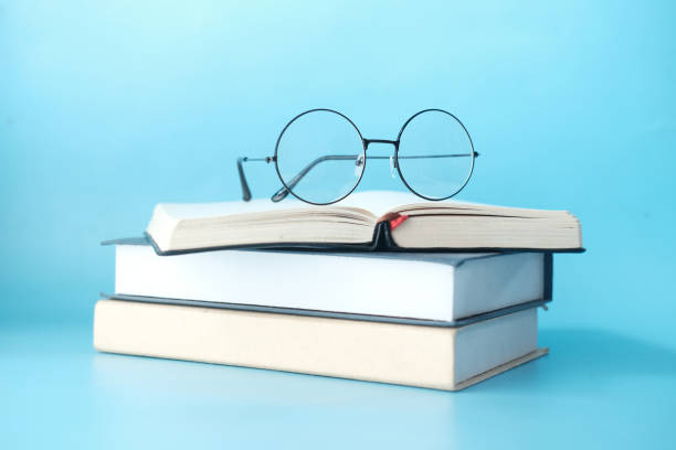 istock stack of books and eyeglass on blue background 1342798047