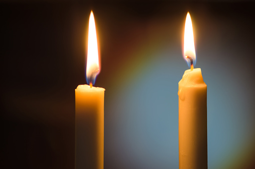 two candles with a bright flame in a room on a blurred background