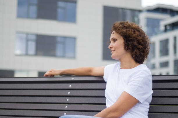 A 45-50 years old woman is sitting on a bench.