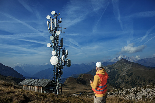 A redhead male engineer utility engineer working at a telecom tower at a mountain site