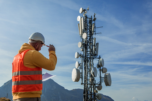 Human hand using mobile phone near 4G,5G communications tower