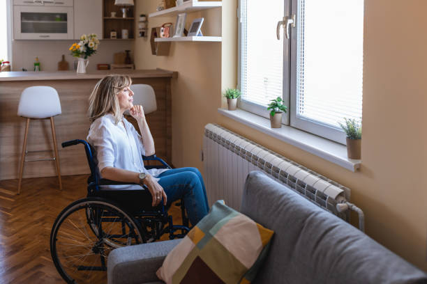 donna matura disabile in sedia a rotelle a casa in soggiorno. - aging process old middle senior adult foto e immagini stock