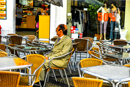 A tourist waiting outside a cafe in the early morning hour on the Rua Augusta in Lisbon, Portugal.