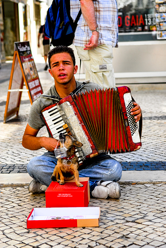 A street musician with his singing dog on a street in Lisbon, Portugal.