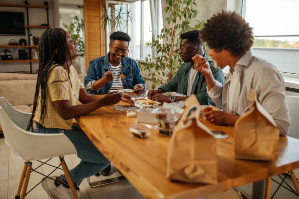Group of young adults eating take out food at home stock photo