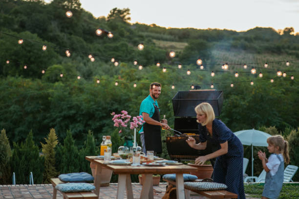istock Young adult man barbecuing while his wife and daughter arranging table 1342811193