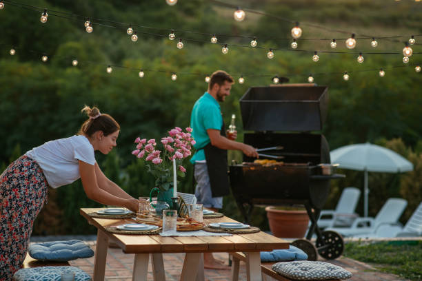 istock Young woman setting dining table while her husband barbecuing near her 1342811197