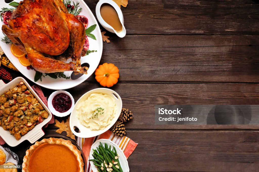 Classic Thanksgiving turkey dinner. Top down view side border on a dark wood background with copy space. Classic Thanksgiving turkey dinner. Top down view side border on a dark wood background with copy space. Turkey, mashed potatoes, stuffing, pumpkin pie and sides. Thanksgiving - Holiday Stock Photo