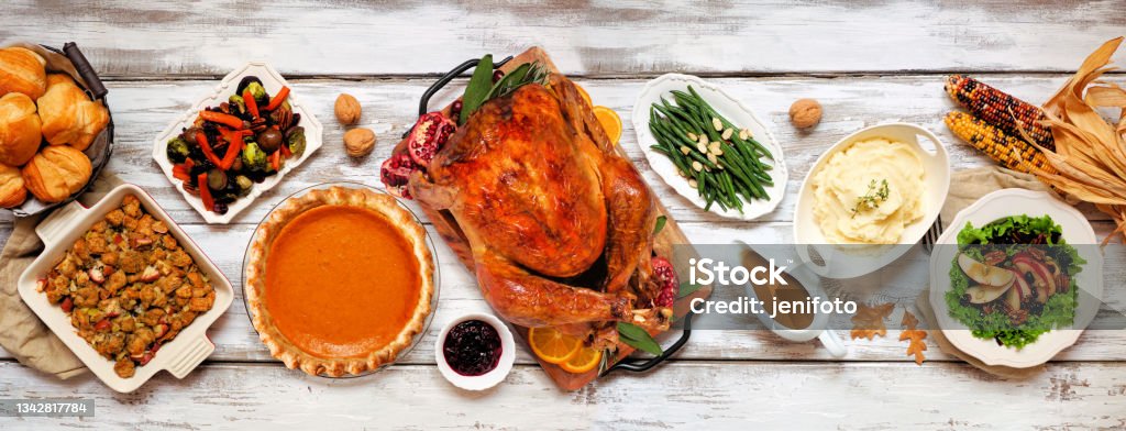 Traditional Thanksgiving turkey dinner above table scene on a rustic white wood banner Traditional Thanksgiving turkey dinner. Above view table scene on a rustic white wood banner background. Turkey, mashed potatoes, stuffing, pumpkin pie and sides. Thanksgiving - Holiday Stock Photo