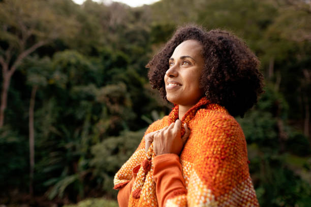 istock Smiling woman wrapped in shawl looking at a scenic forest view 1342820042