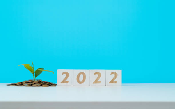 istock Heap of coins and number 2022 on white table 1342826485