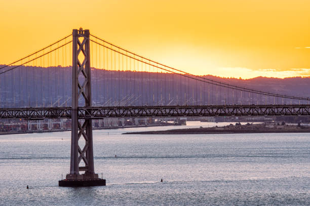 oakland bay bridge mit aufgehender sonne san francisco - san francisco county embarcadero center bay bridge built structure stock-fotos und bilder