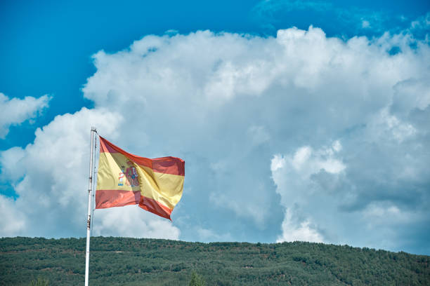 istock Spanish flag over blue sky with clouds - Constitutional Spanish flag 1342878008
