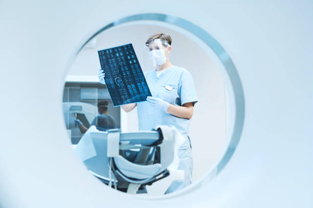 istock MRI bore view of radiologist in safety face shield viewing x-ray image while analyzing results of computer tomography 1342882406