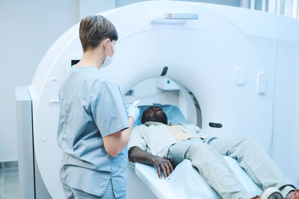 istock Young nurse in mask pressing start button on control panel of MRI scanner while performing procedure in clinic 1342882441