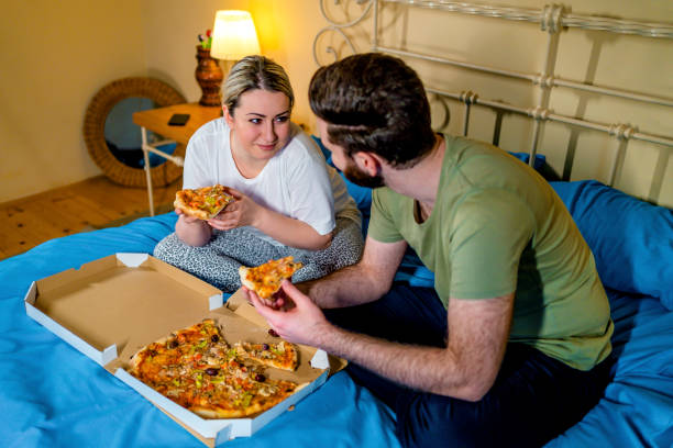 istock Happy couple eating pizza on the bed 1342885810