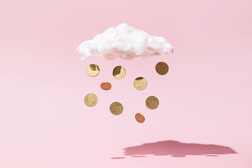 Concepto de lluvia de dinero hecho de monedas de oro y nube blanca sobre fondo rosa photo