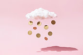 Money rain concept made of gold coins and white cloud on pink background