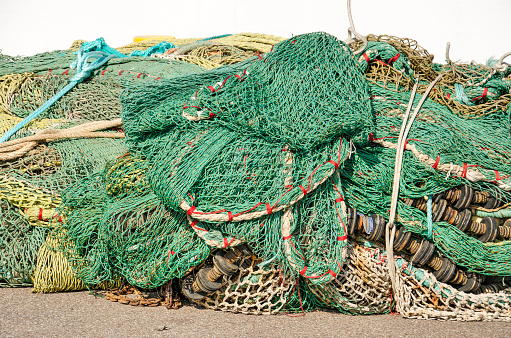 Large tangle of fishing nets on the quay in a fishing harbour on a sunny day