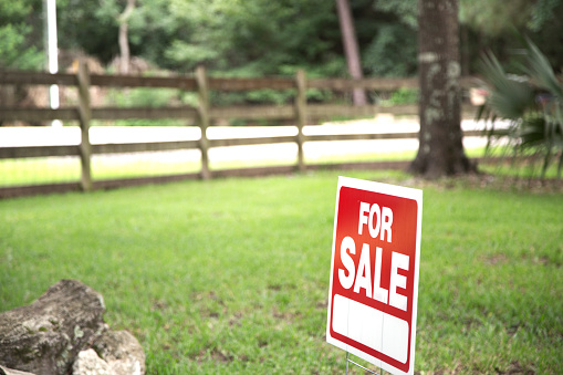 Real estate sign on Vacant Lot or front yard of Home for Sale.