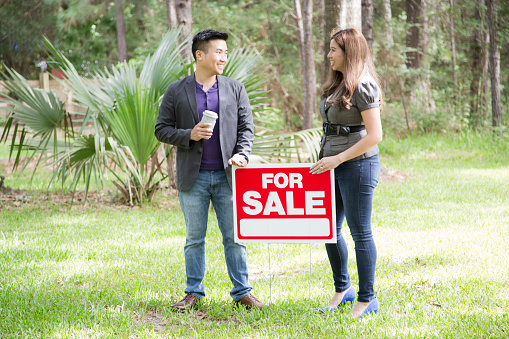 Real Estate for sale.  Vacant Lot has many possibilities.  Mid adult couple looking at empty lot for sale.