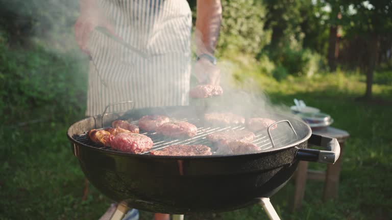 Unrecognizable person, grilling the beef meat, and bacon on the bbq, during bbq party